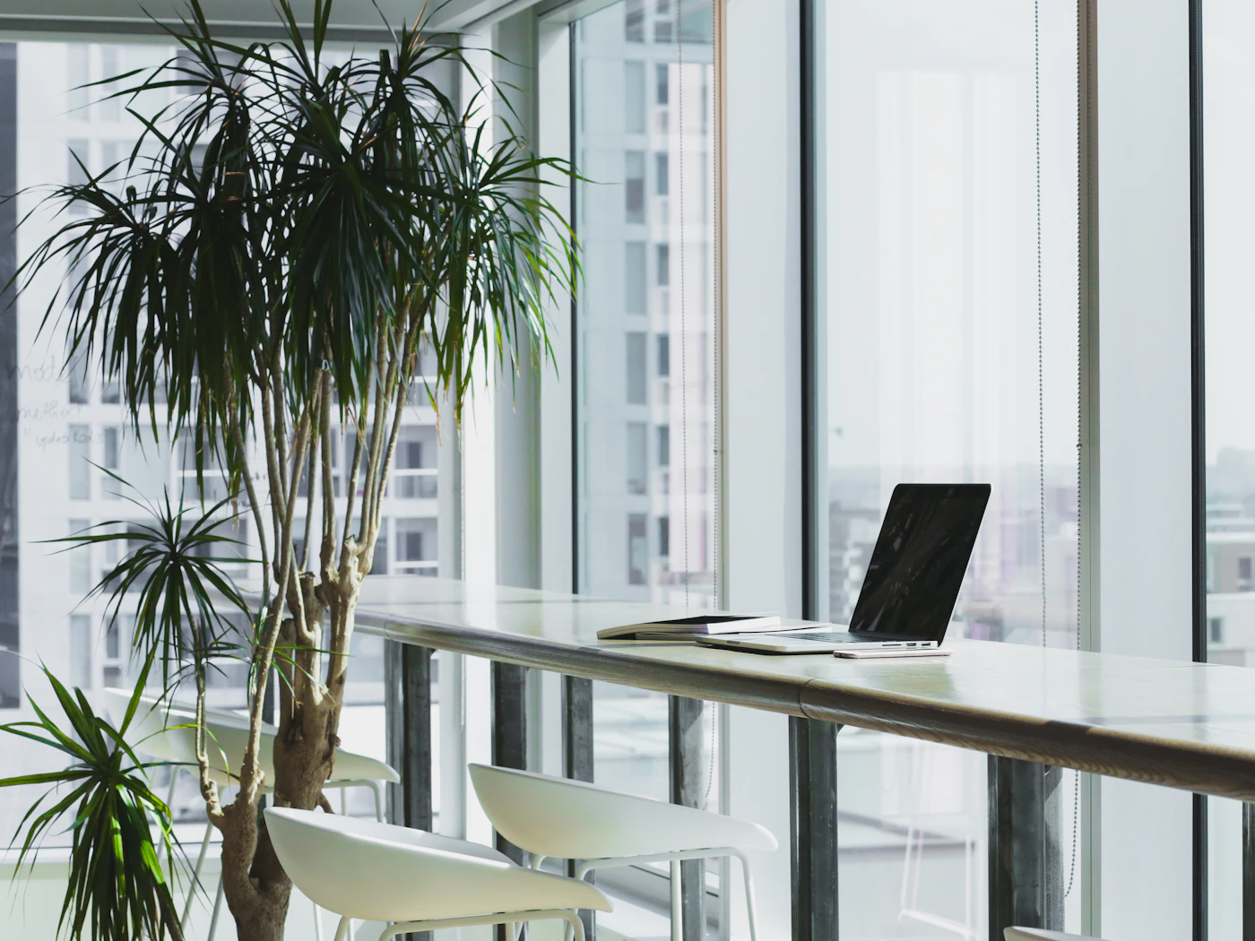 A desk against a bright floor-to-ceiling office window